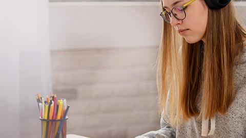 Teen wearing headphones studying at desk